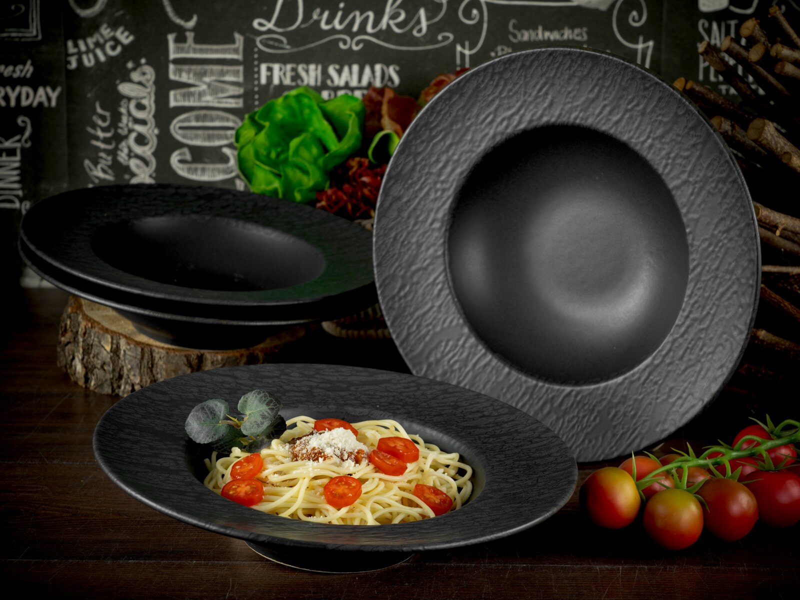 Creatable Pastateller 4-tlg SCHIEFER Schwarzer, strukturierter Gourmet-Tiefen-Teller/Schale aus Keramik in schräger Frontansicht, als Pastateller angerichtet, mit weiteren passenden Tellern im Hintergrund.