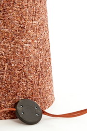 Detailopname vanuit zij- en achterperspectief van een warmbruin gemêleerde stoffen lamp met bijpassend textielsnoer en zwarte voetschakelaar.