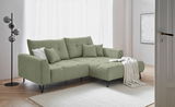 Grünes Ecksofa mit Ottomane rechts, dekoriert mit Kissen und Decke, in einem modernen Wohnzimmer mit hellem Holzboden und Stehlampe, Perspektive von vorne links.