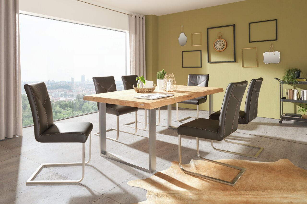 Valdera Tafelblad 180 x 90 MEMORY Een moderne eetkamer met een grote houten tafel en zes zwarte stoelen, gezien vanuit de zijkant.