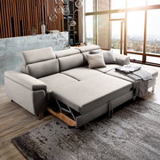 Großes, modernes Ecksofa in hellem Grau mit Schlaffunktion, abgebildet in einem stilvollen Wohnzimmer mit Blick auf die Stadt durch große Fenster. Perspektive von vorne links.