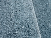 Nahaufnahme eines blauen Uni-Teppichs mit weicher, flauschiger Textur, seitliche Perspektive