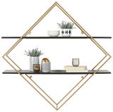 Wandregal mit geometrischem Design, zwei schwarzen Regalböden und goldfarbenem Rahmen, frontal abgebildet. Dekoriert mit Pflanzen, Schalen und Büchern.