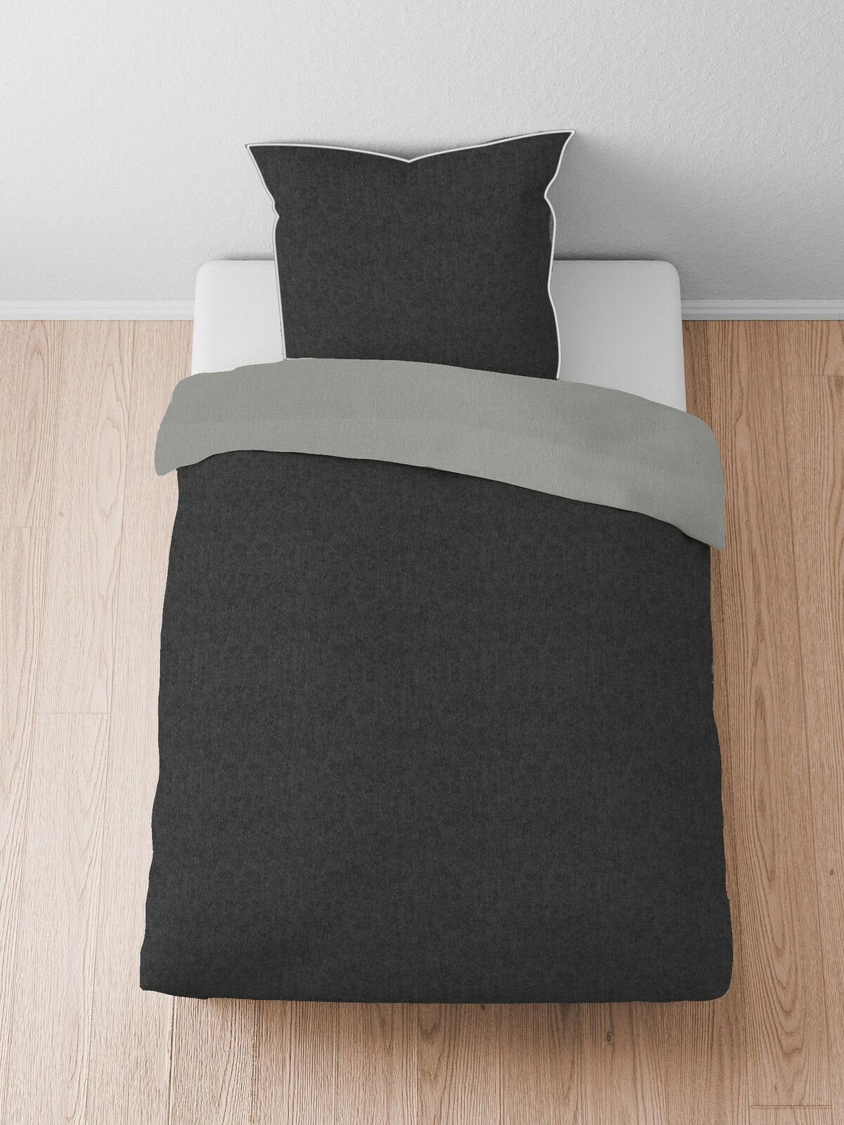 Bettwäsche-Set aus Melange-Flanell in Dunkelgrau, bestehend aus einem Kissenbezug und einem Bettdeckenbezug, auf einem Bett von oben fotografiert.