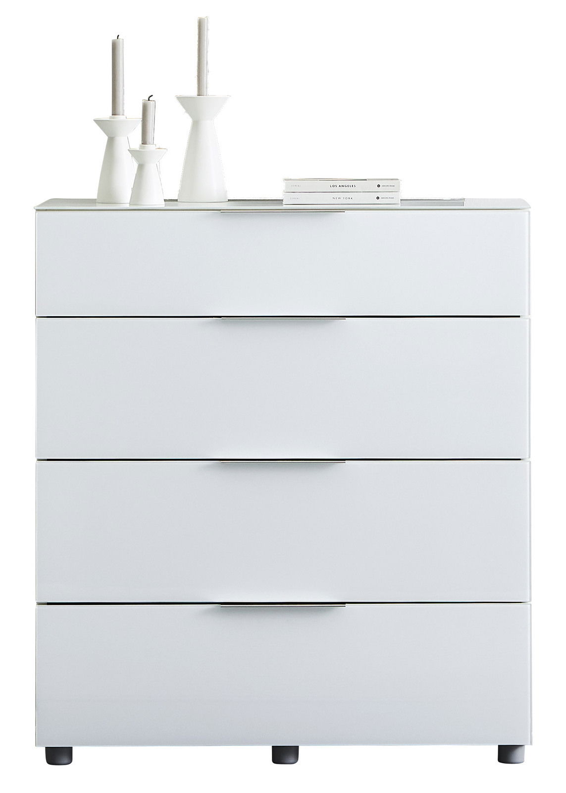 Weiße Schubkastenkommode mit vier Schubladen, dekoriert mit weißen Kerzenhaltern und Büchern, frontal betrachtet.