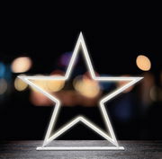 LED-Stern in Sternform, leuchtend auf einem Tisch vor unscharfem Hintergrund, frontal betrachtet
