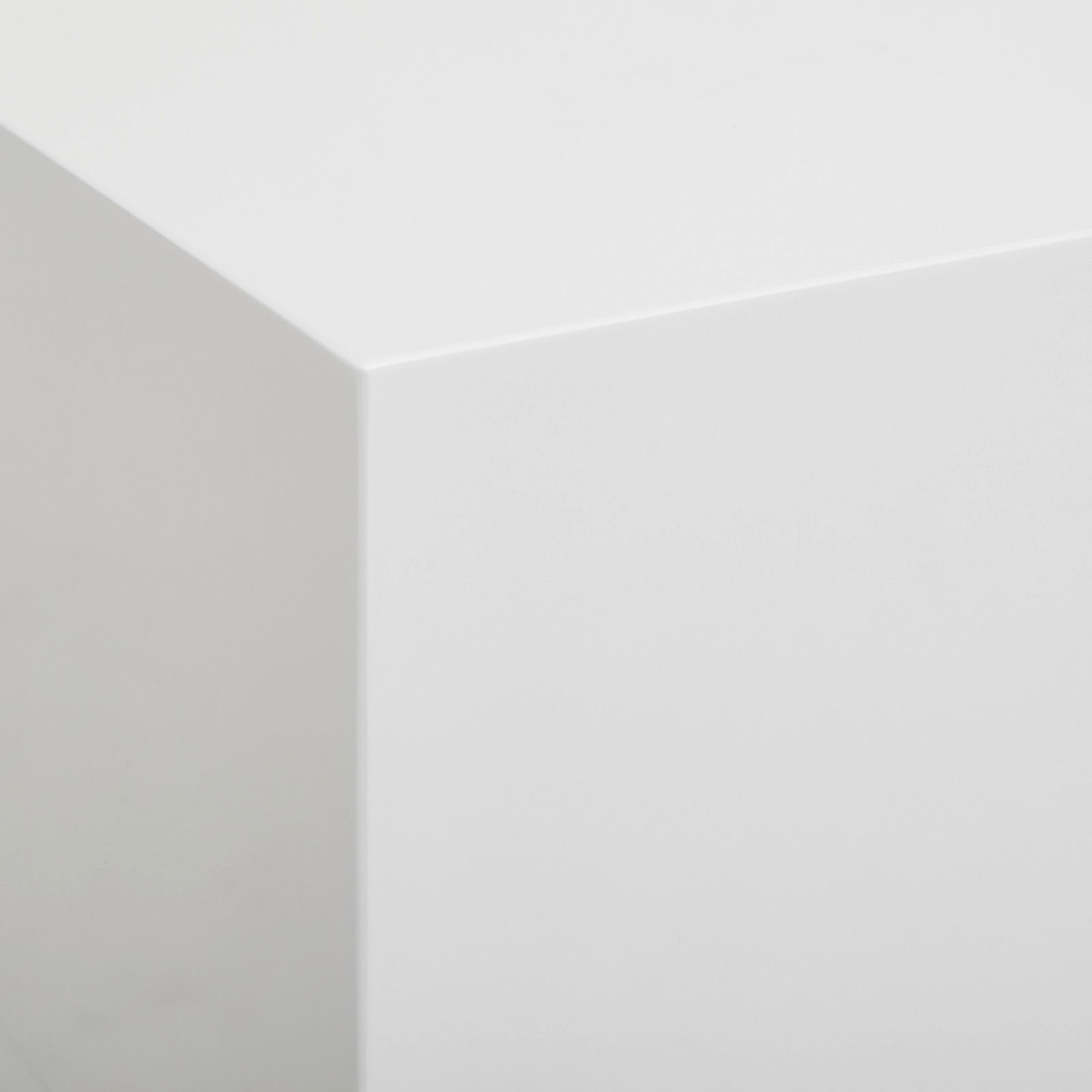 Nahaufnahme einer weißen, glatten Ecke eines Lowboards aus der Perspektive von oben.