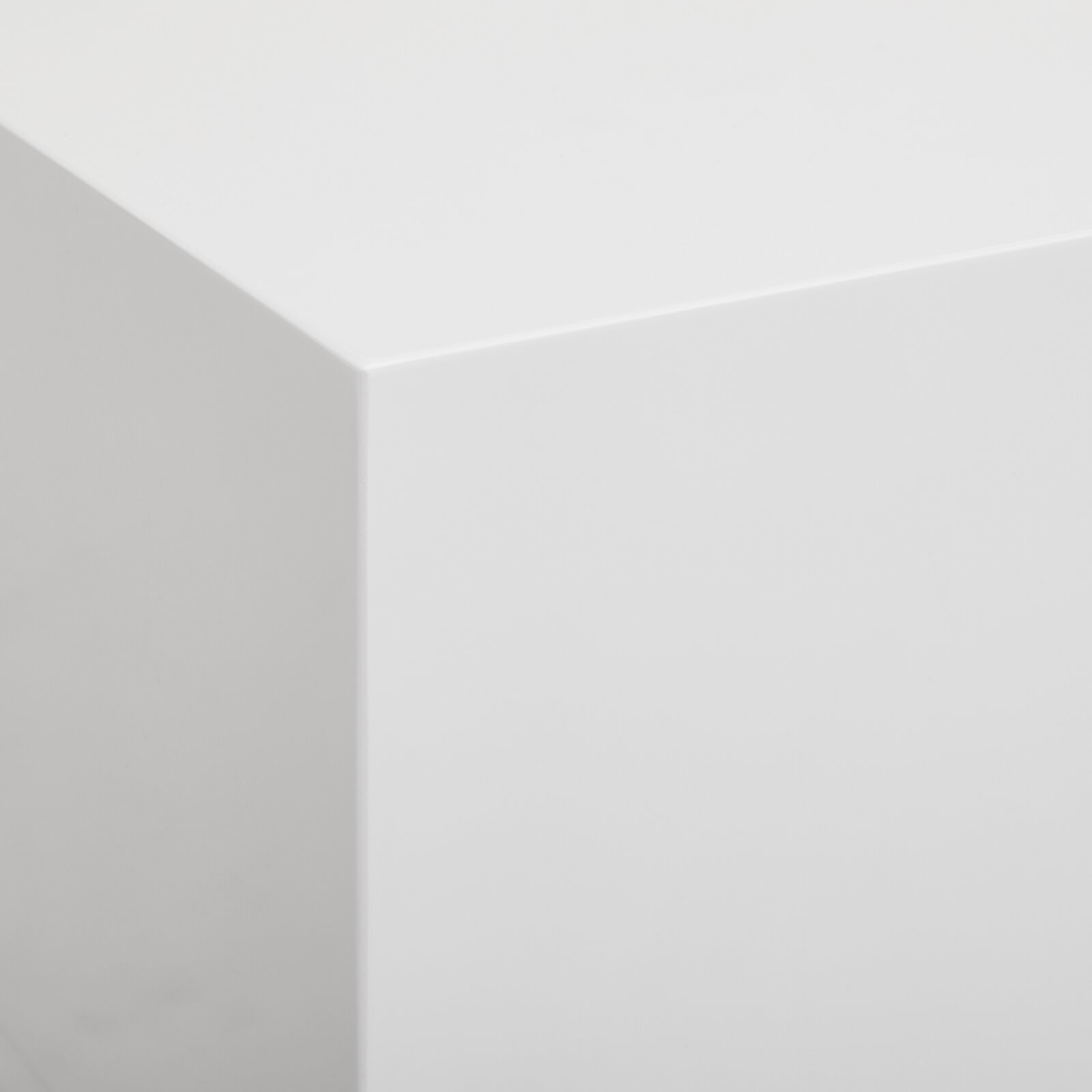 Nahaufnahme einer weißen, glatten Ecke eines Lowboards aus der Perspektive von oben.