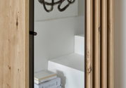 Detailweergave van een compacte kapstok met houten bekleding en spiegel, zijaanzicht.