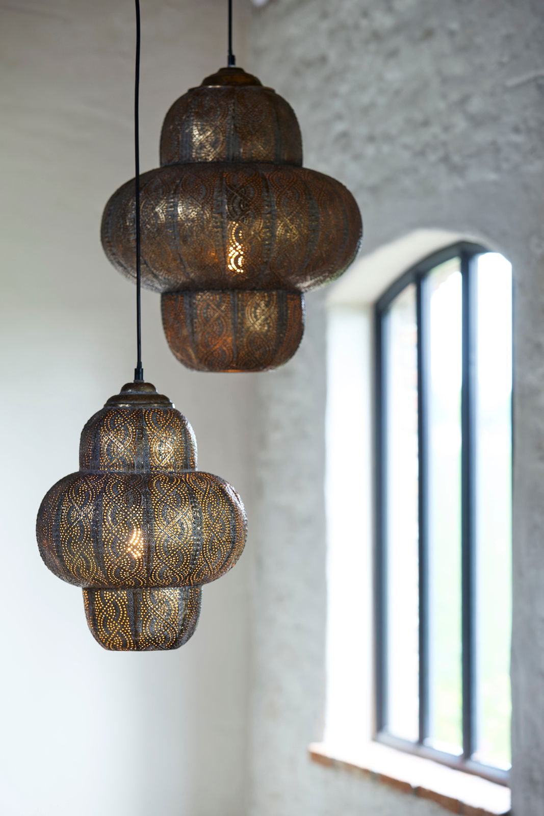 Zwei orientalische Hängeleuchten aus Metall mit filigranem Muster, seitliche Perspektive, im Hintergrund ein Fenster.