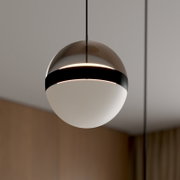 Moderne kugelförmige Pendelleuchte mit halbtransparentem braun getöntem Schirm, schwarzem Ring und weißem Diffusor, warm leuchtend, Nahaufnahme in leichter Untersicht
