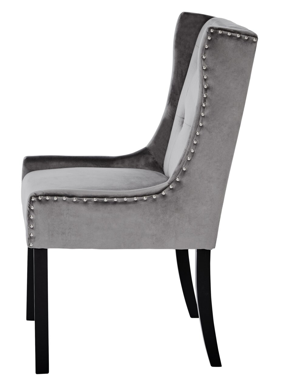 Zijaanzicht van een elegante grijze stoel met fluwelen bekleding en studs.