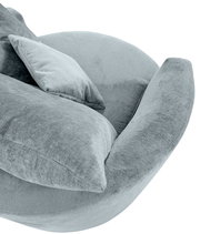 Gemütlicher Sessel in hellgrauem Stoff mit weichen Kissen, seitliche Perspektive