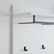 Garderobenpaneel in seitlicher Perspektive mit weißem Regalbrett und schwarzen Haken.