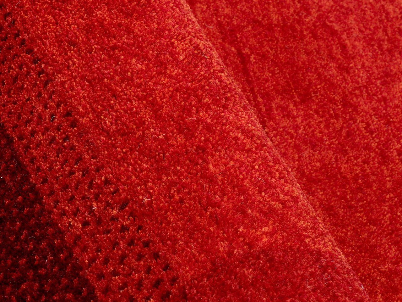 Nahaufnahme eines roten Wollteppichs mit feiner Textur und diagonaler Perspektive