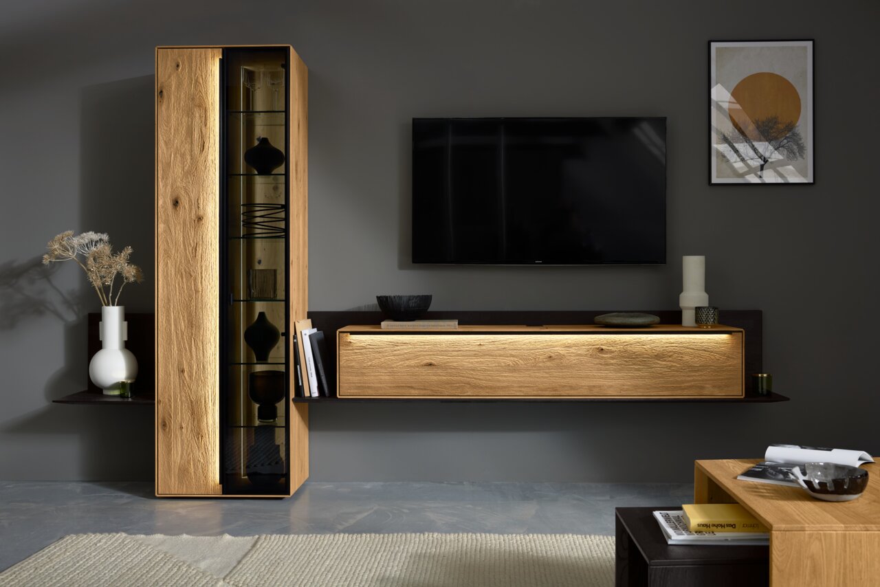 Moderne Wandkombination in Holzoptik mit LED-Beleuchtung, bestehend aus einem hohen Schrank mit Glastür und einem breiten, flachen Sideboard. Perspektive von vorne.