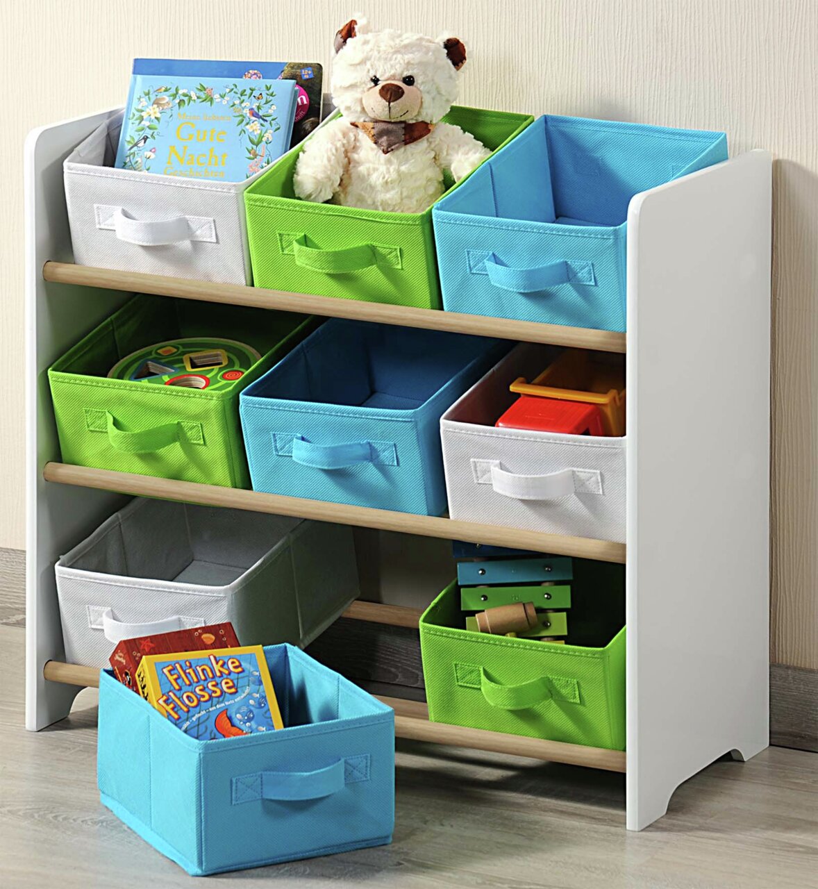 Weißes Aufbewahrungsregal mit bunten Stoffboxen, gefüllt mit Spielzeug und Büchern, aus seitlicher Perspektive.