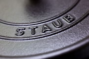 Nahaufnahme des Deckels eines runden Bräters der Marke Staub, mit Fokus auf das eingeprägte Logo.