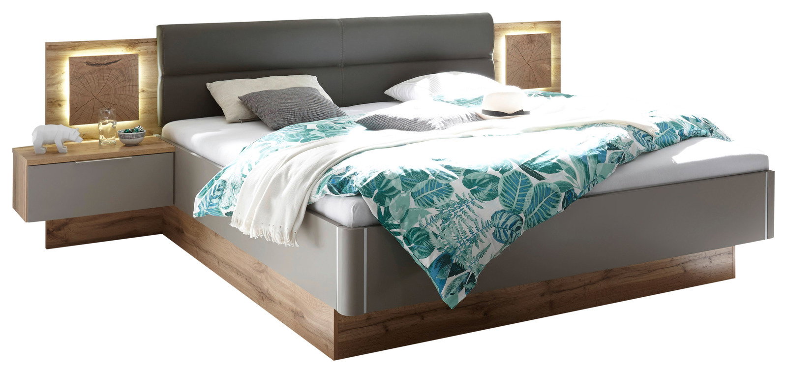 Bettanlage mit grauem Kopfteil, integrierter Beleuchtung und Nachttisch, aus Holz und grauem Material, Perspektive von schräg vorne