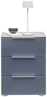 Moderne Nachtkonsole mit drei Schubladen in grauer Farbe, darauf eine weiße Tischlampe, eine Schale und Bücher. Frontalansicht.
