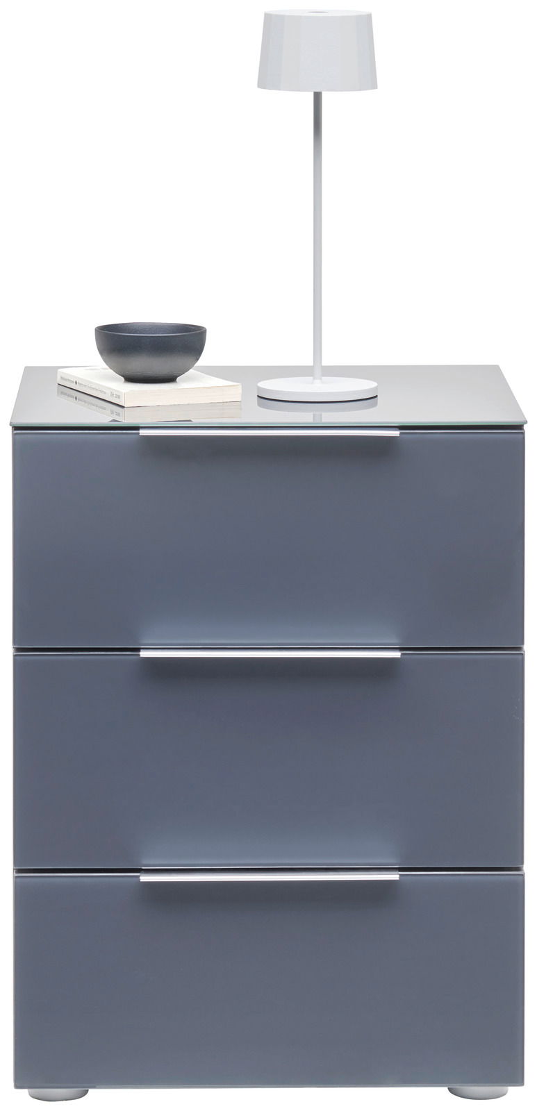 Moderne Nachtkonsole mit drei Schubladen in grauer Farbe, darauf eine weiße Tischlampe, eine Schale und Bücher. Frontalansicht.
