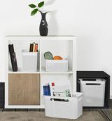 Quadratische Aufbewahrungsboxen in einem Regal, gefüllt mit Büchern und Garn, aus frontaler Perspektive.