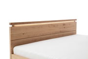 Holzbett mit natürlicher Maserung, seitliche Perspektive auf das Kopfteil