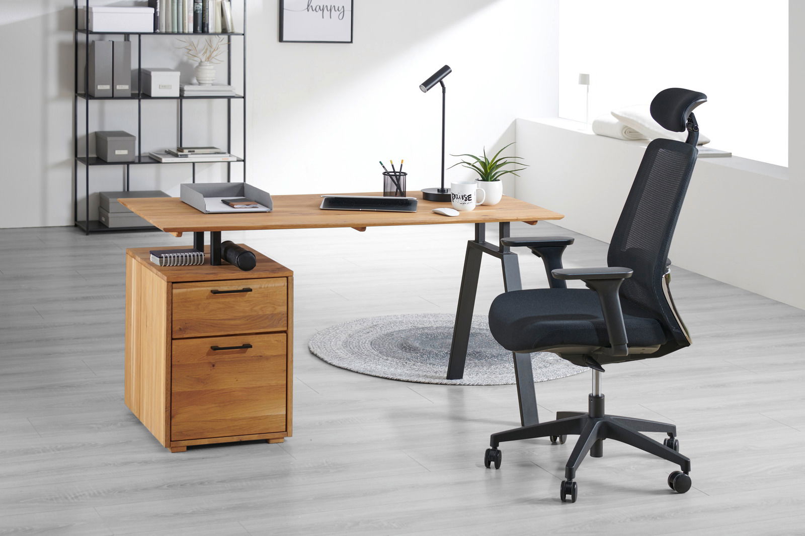 Moderner Drehstuhl in einem hellen Büro, seitliche Perspektive, neben einem Schreibtisch aus Holz mit Schubladen und Büromaterial.