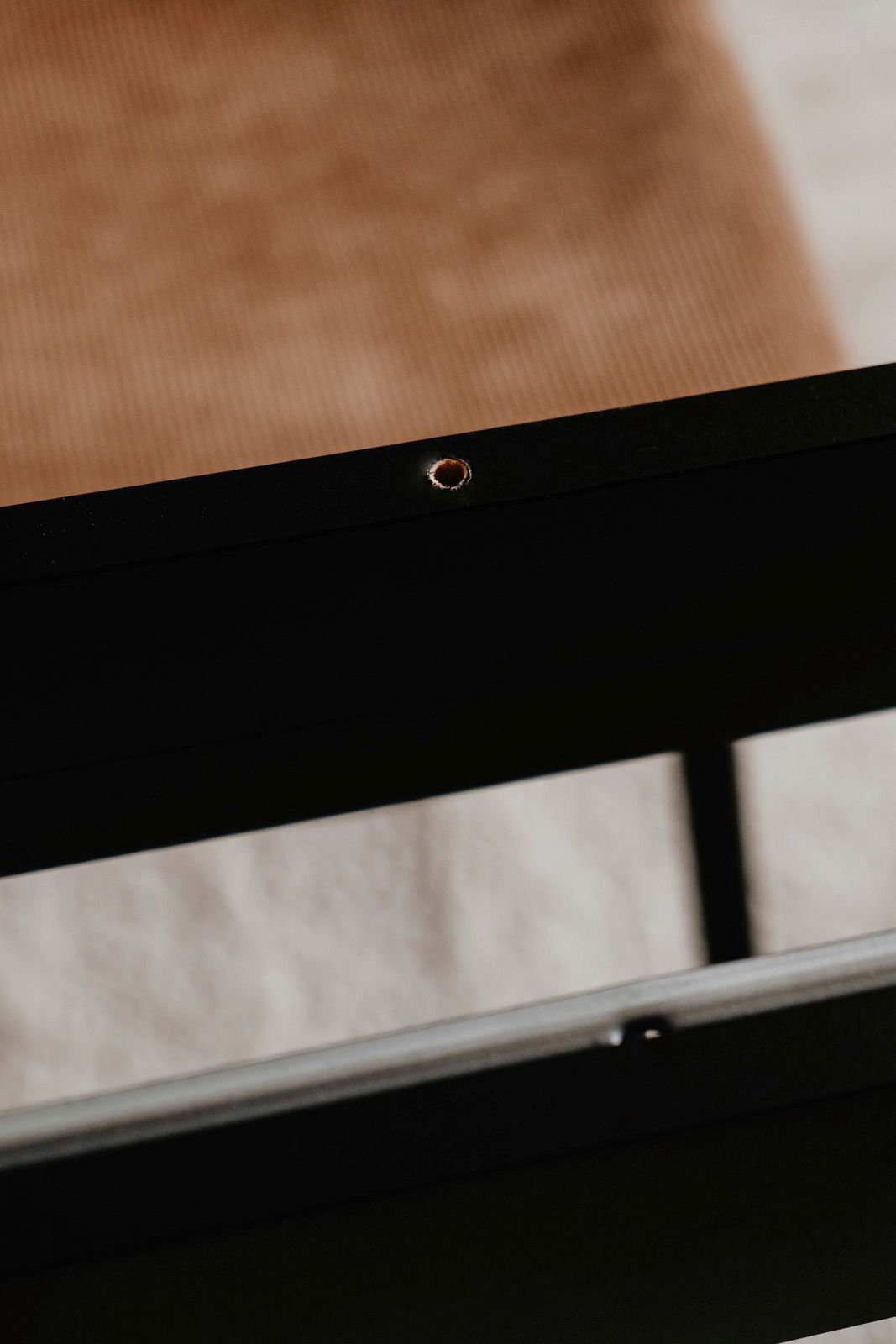 Nahaufnahme eines schwarzen Tischgestells mit sichtbarer Schraubenöffnung, seitliche Perspektive.