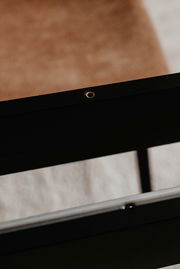 Nahaufnahme eines schwarzen Tischgestells mit sichtbarer Schraubenöffnung, seitliche Perspektive.