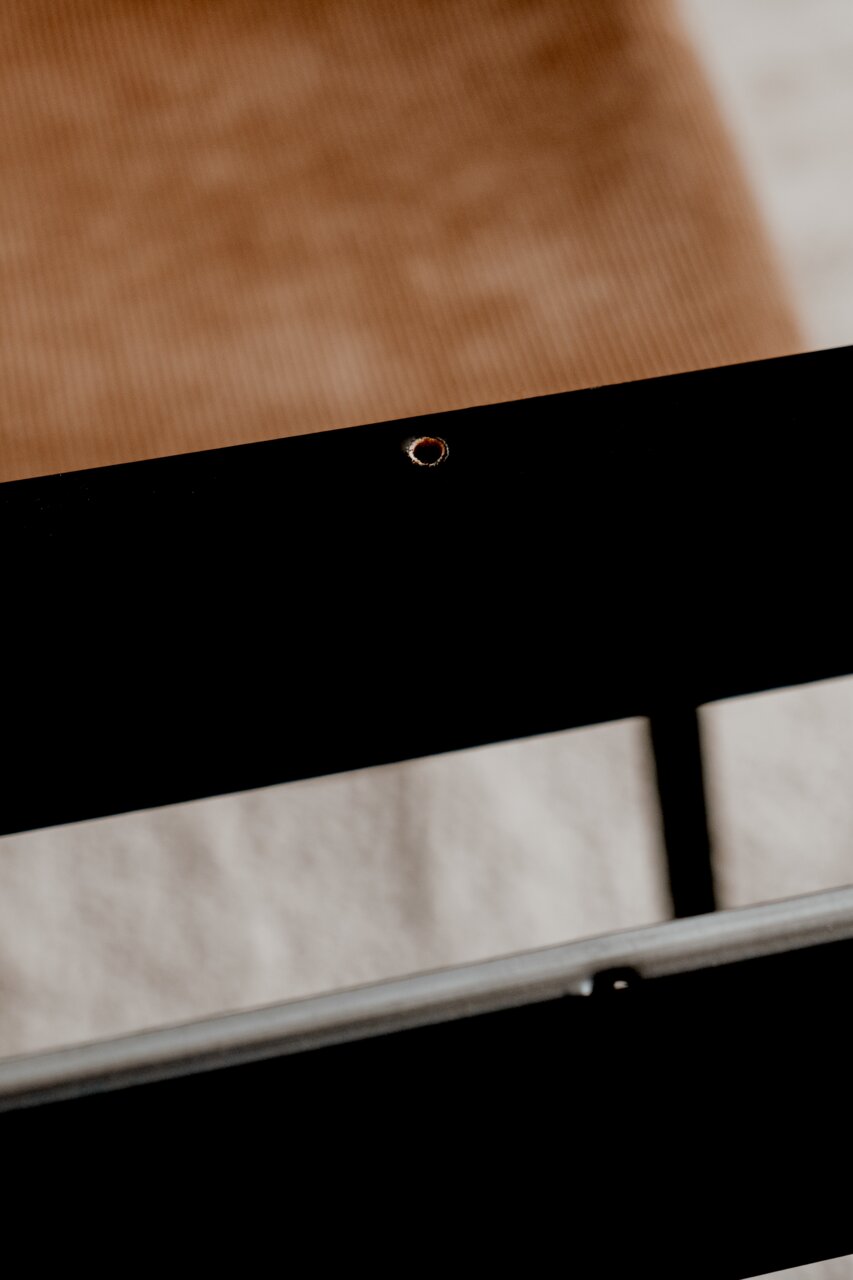 Nahaufnahme eines schwarzen Tischgestells mit sichtbarer Schraubenöffnung, seitliche Perspektive.