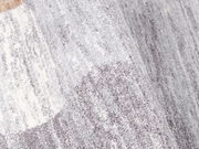 Nahaufnahme eines grauen und weißen Frisé-Teppichs mit weicher Textur und leichtem Farbverlauf.