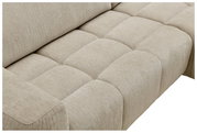 Nahaufnahme eines beigen Ecksofas mit gepolsterten Sitzflächen, seitliche Perspektive.