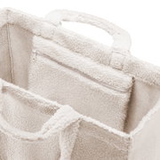 Nahaufnahme einer weichen, cremefarbenen Tasche mit Reißverschluss und Tragegriffen, von oben betrachtet.