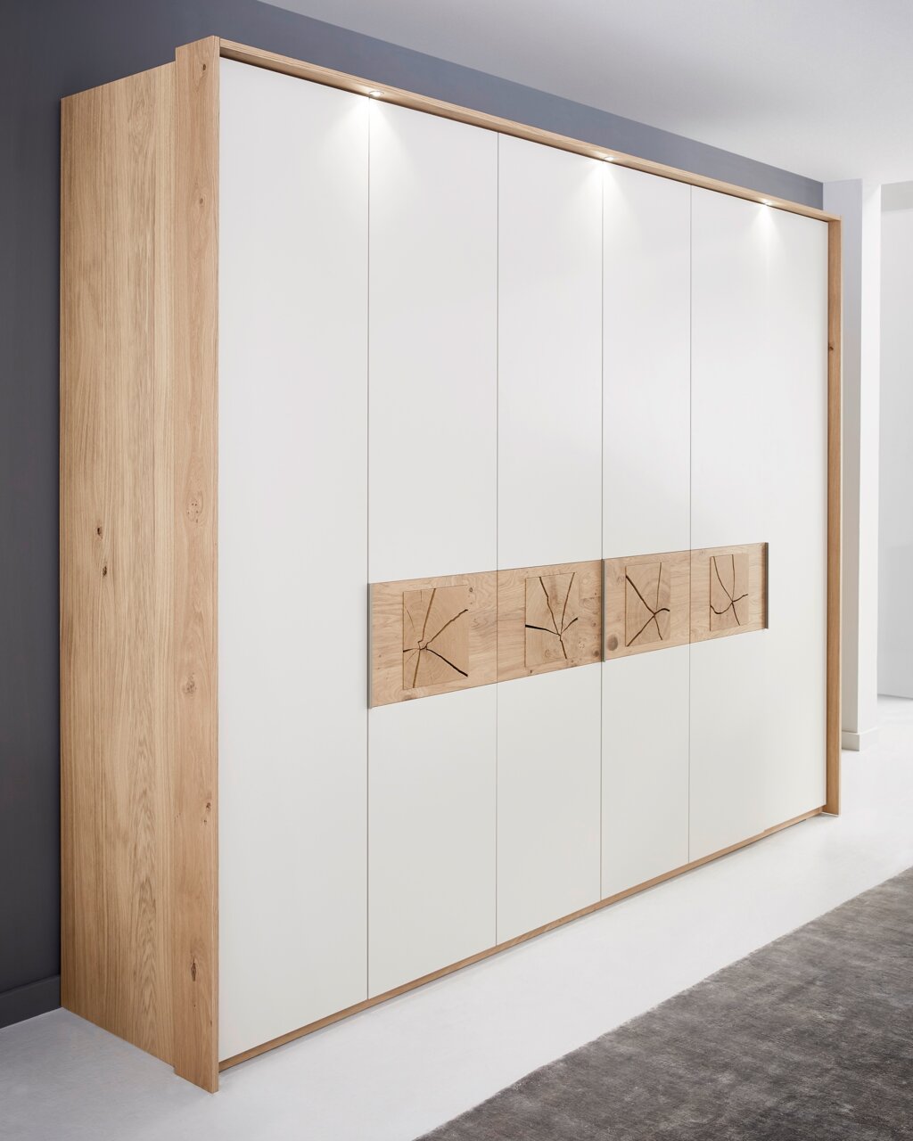 Sechstüriger Drehtürenschrank in Holzoptik mit weißen Fronten und dekorativen Holzelementen, seitliche Perspektive.