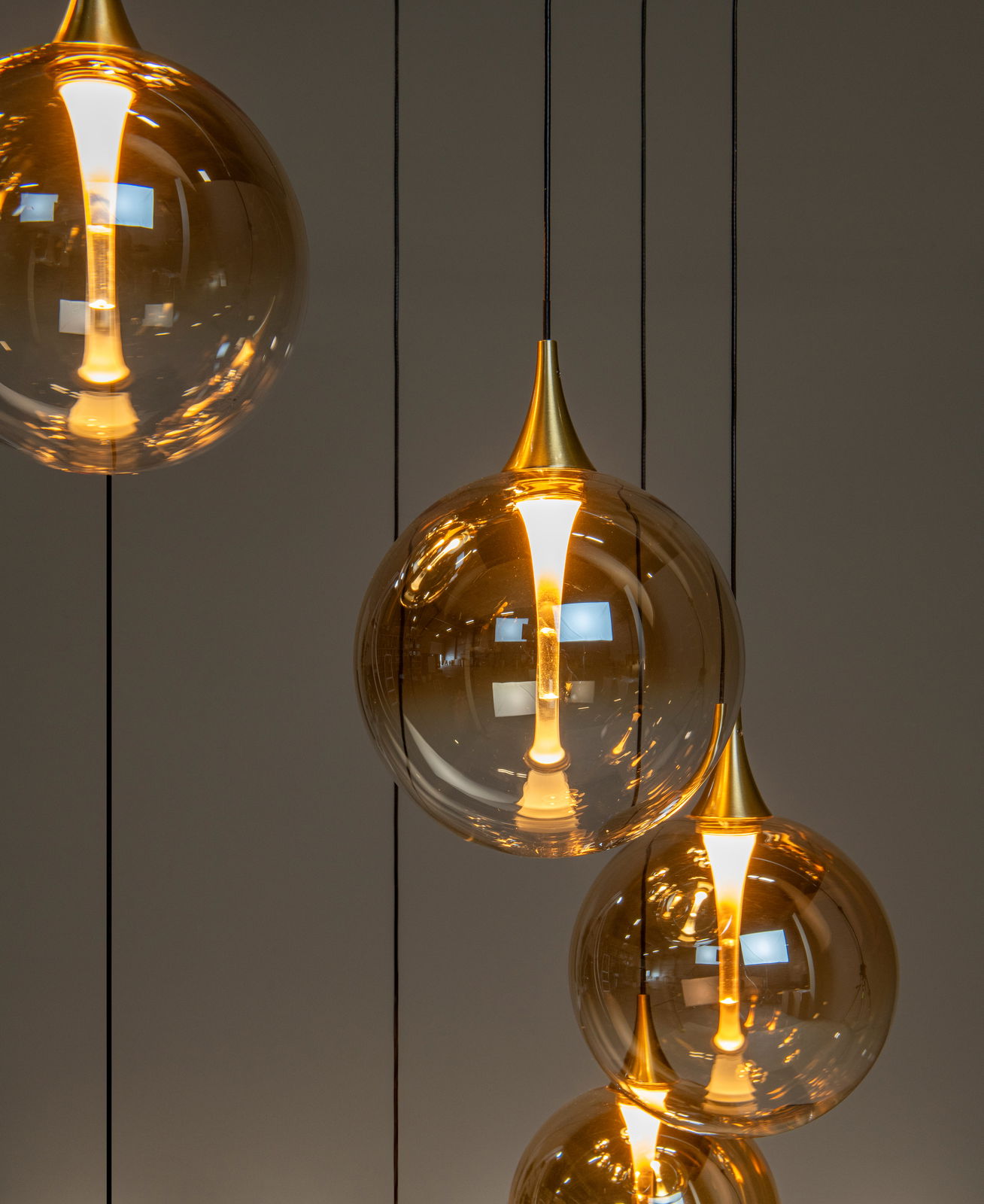 Moderne Hängeleuchte mit mehreren goldenen, kugelförmigen Lampenschirmen aus Glas, von der Seite betrachtet.