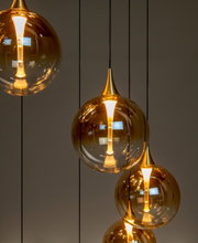 Moderne Hängeleuchte mit mehreren goldenen, kugelförmigen Lampenschirmen aus Glas, von der Seite betrachtet.