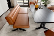 Moderne Esszimmer-Sitzbank in braunem Leder mit schwarzem Metallgestell, neben einem dunklen Esstisch, aus der Vogelperspektive fotografiert.