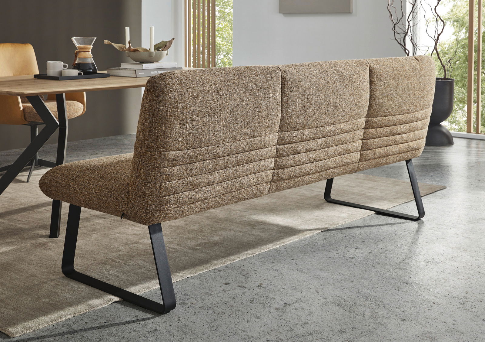Rückansicht einer modernen Sitzbank mit braunem Stoffbezug und schwarzen Metallbeinen in einem Esszimmer.