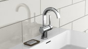 Moderne Waschtischarmatur aus Chrom in seitlicher Perspektive, montiert auf einem weißen Waschbecken mit Seifenschale.