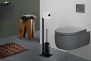 Modernes Badezimmer mit wandhängendem WC in Dunkelgrau, schwarzem freistehendem Toilettenpapierhalter mit Rollenhalter und WC-Bürste; Ansicht schräg von vorne rechts.