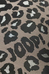 Nahaufnahme einer Zierkissenhülle mit Leopardenmuster und dem Schriftzug 'JOOP!' in Schwarz und Weiß auf grauem Hintergrund.