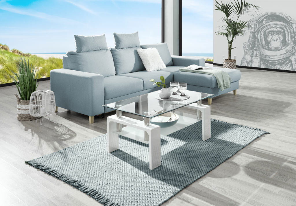 Helles Wohnzimmer mit einer modernen, hellblauen Eckcouch und einem Glastisch, Blick aus der Seitenperspektive.