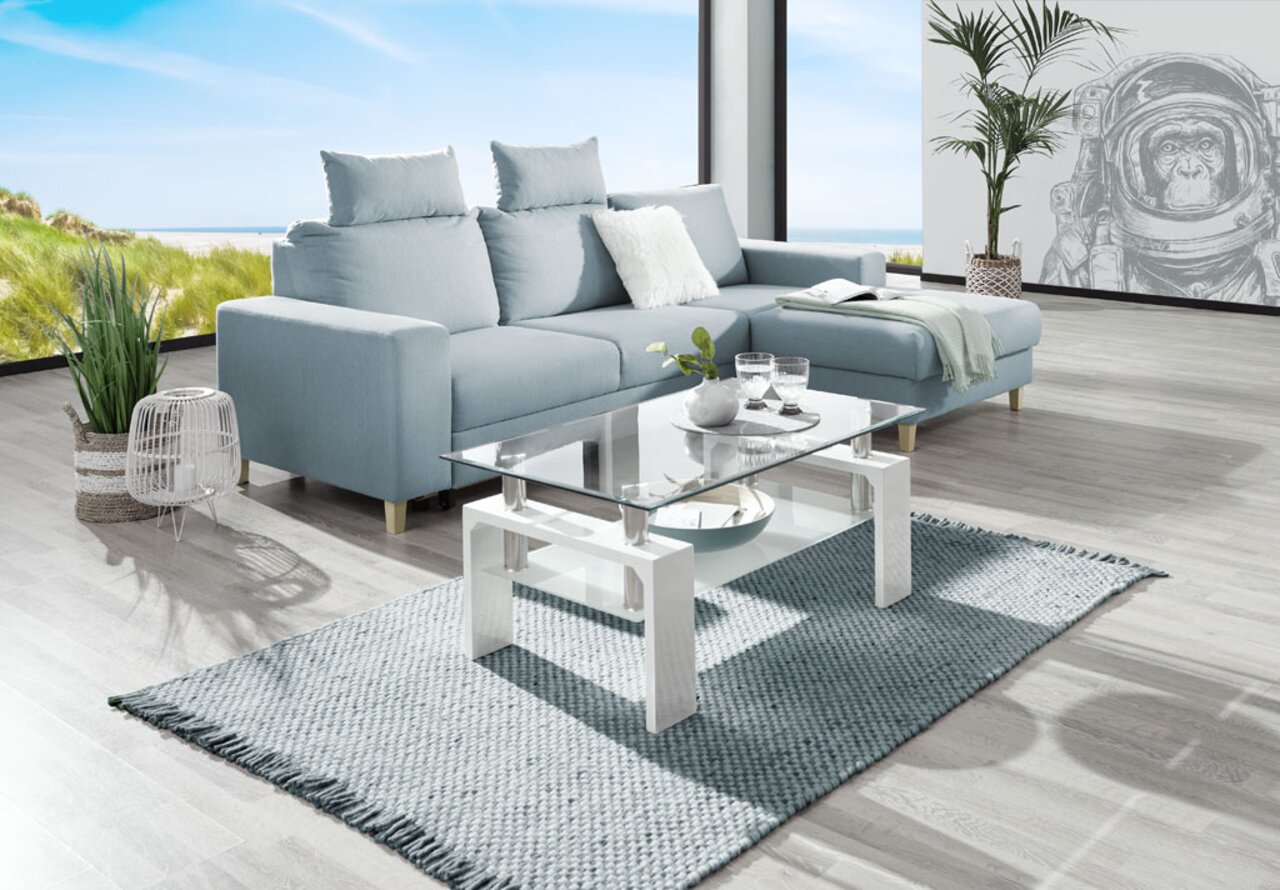 Helles Wohnzimmer mit einer modernen, hellblauen Eckcouch und einem Glastisch, Blick aus der Seitenperspektive.
