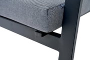 Close-up van een Comfort Plus stapelstoel met grijze bekleding en een zwart metalen frame, gezien vanaf de zijkant.