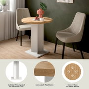 Runder kleiner Esstisch/Bistrotisch mit Holzplatte und weißem Metallgestell im Industrial-Look, zwischen zwei gepolsterten Stühlen im Wohnraum, perspektivisch in schräger Frontansicht