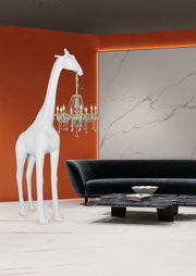 Weiße Giraffen-Skulptur als Stehlampe mit hängendem Kristall-Kronleuchter im modernen Wohnzimmer, frontale Perspektive