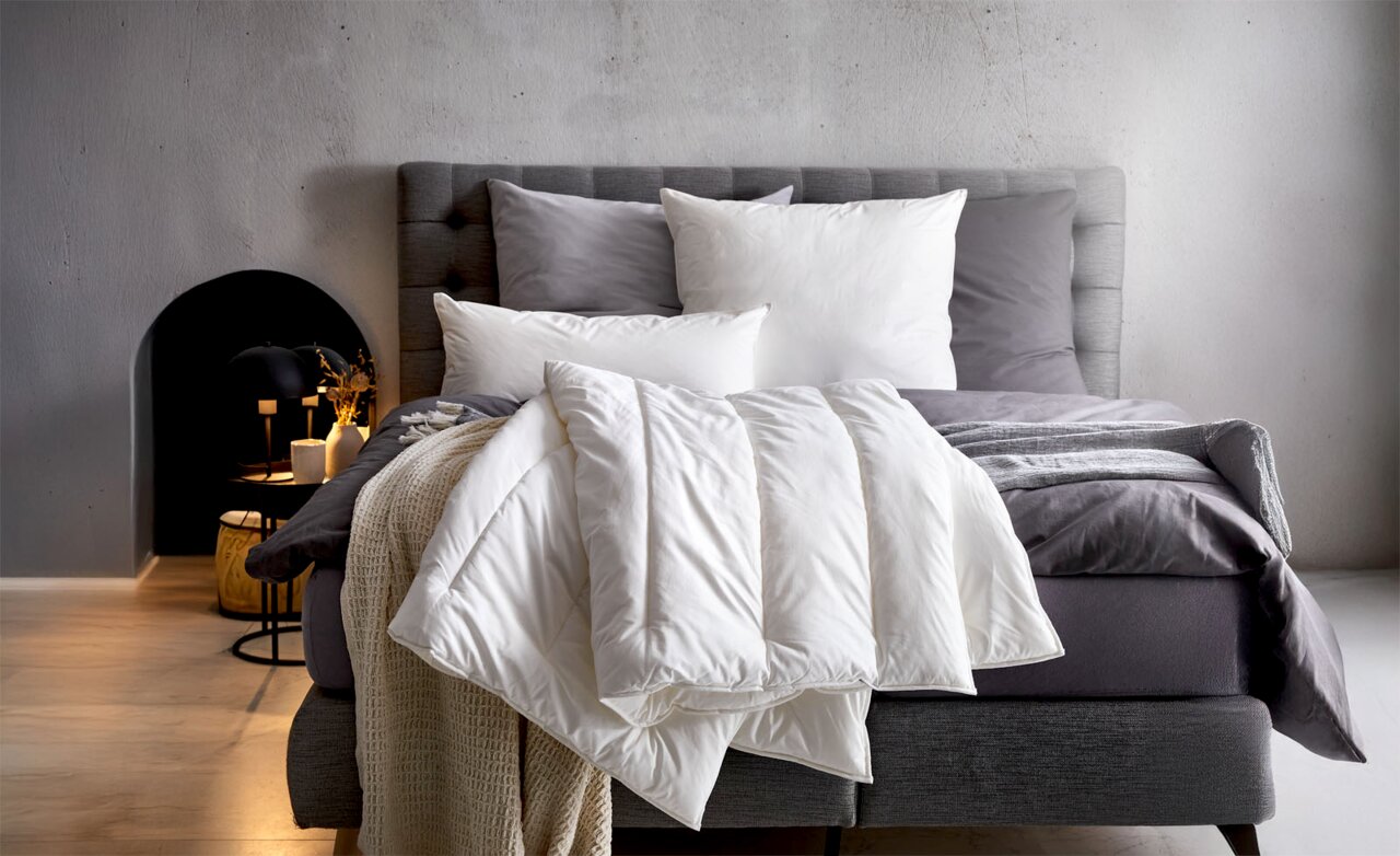 Centa Star Duobett VEGAN DREAM Gemütliches Schlafzimmer mit einem stilvoll gemachten Bett, das mit weißen Kissen und einer weißen Bettdecke dekoriert ist. Die Perspektive zeigt das Bett von vorne.