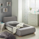 Grauer Funktionssessel in einem modernen Schlafzimmer, von der Seite betrachtet, mit ausgezogener Liegefläche und dekorativen Elementen im Hintergrund.