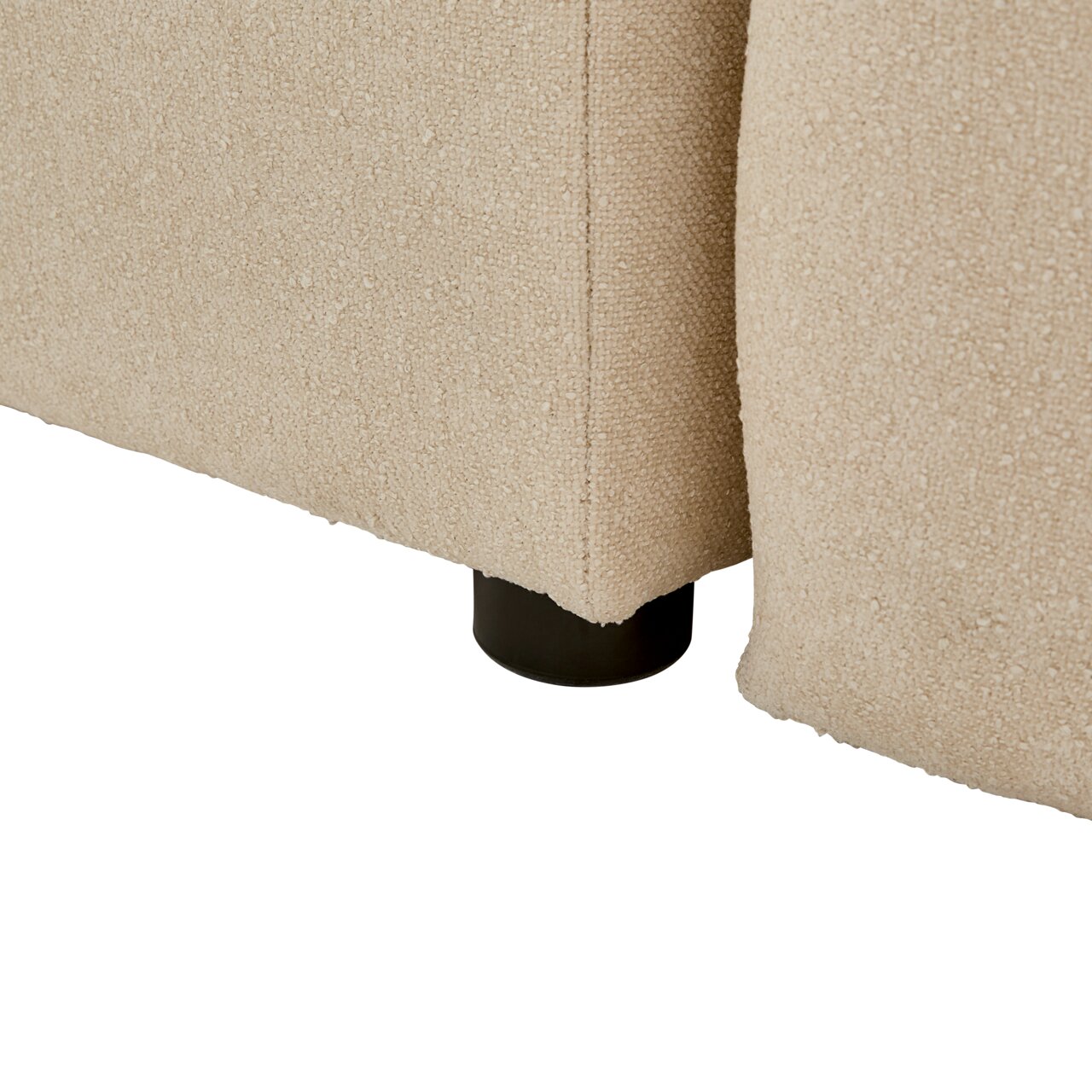 Nahaufnahme der Ecke eines beige gepolsterten Boxbetts mit schwarzem Fuß, seitliche Perspektive